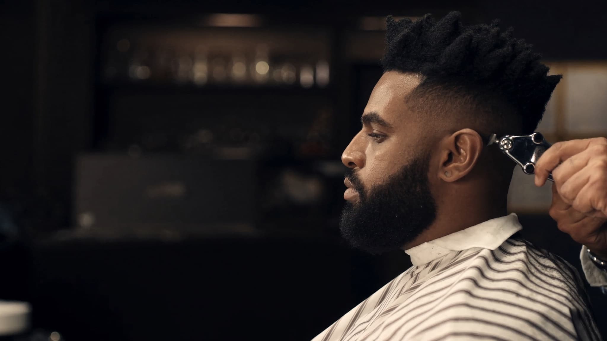 Barbier réalisant un dégradé à la tondeuse sur un client